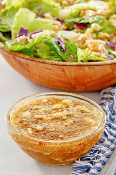 a salad with dressing in a wooden bowl next to a blue and white napkin on the table