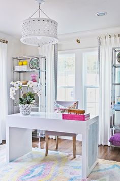 a white desk in the middle of a living room with lots of furniture and decor