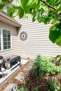 an outside view of a house with a grill and some plants in the front yard