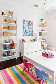 a child's room with white shelves and colorful rugs