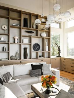 a living room filled with white furniture and lots of shelves on the wall behind it