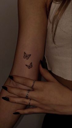 two women's hands with butterfly tattoos on their wrist and one is holding the other hand