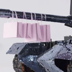 pink shopping bags hanging from the side of an armored vehicle with camouflage print on it