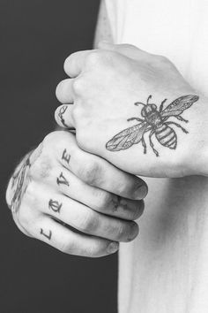 two people holding hands with tattoos on their wrists and one has a bee tattooed on the wrist