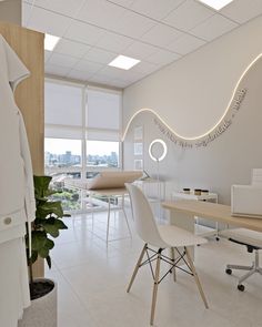 an office with white furniture and large windows