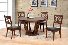 a dining room table with four chairs in front of a brick wall and rug on the floor