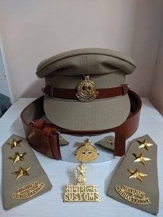 an uniform hat and other items are on a white tablecloth with gold trimmings