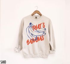 Go bananas for vintage style with our "That's Bananas" retro inspired crewneck sweatshirt. This fabulous graphic will be printed on a Gildan 18000 Unisex Sweatshirt which runs true to size. If you are looking for an oversized fit, we recommend sizing up. Please refer to the size chart in the images. We use professional quality DGT printing on all our apparel. Direct-to-garment, or DTG, is a high quality printing method that sprays ink directly onto the garment so there is no peeling or cracking. Banana Sweater, Retro Long Sleeve Sweatshirt With Character Print, Fruit Sweatshirt, Funny Graphic Print Crew Neck Sweatshirt, Banana T Shirt, Food Pun, Food Shirt, Go Bananas, Food Contest