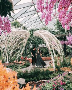 two people standing in a garden with flowers