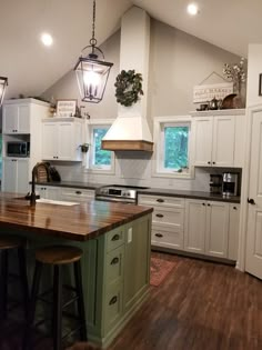 a large kitchen with white cabinets and wooden counter tops, along with two stools