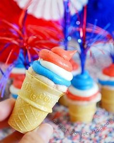 a hand holding an ice cream cone with red, white and blue decorations