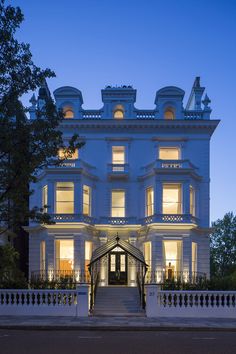 a large white building with lots of windows and lights on it's front entrance