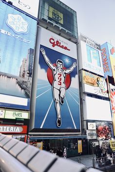 a large advertisement on the side of a tall building in a city with people walking around