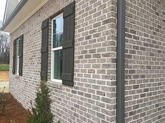 the side of a brick building with green shutters