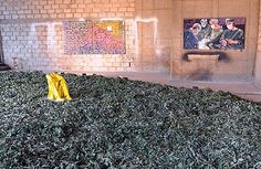 a pile of green leaves sitting in front of a painting on the side of a building