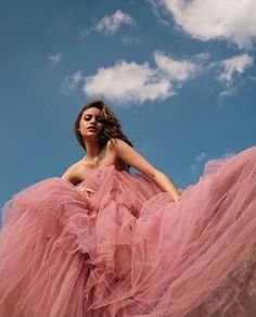 a woman in a pink dress is posing for the camera