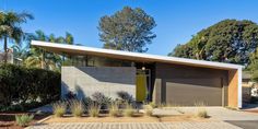 a modern house in the middle of palm trees and plants on either side of it