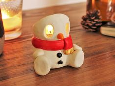 a snowman candle holder sitting on top of a wooden table