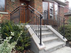 a set of stairs leading to the front door of a brick house with wrought iron railings