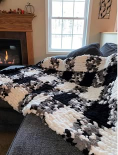 a living room with a fire place and a blanket on the couch in front of it