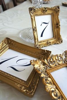 the table is set up with gold frames and place cards