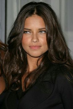 a close up of a person with long brown hair and blue eyes wearing a black top