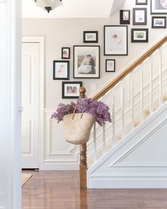 a basket filled with purple flowers sitting on top of a wooden banister next to stairs