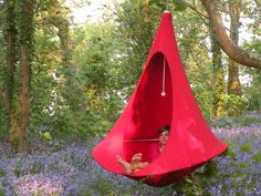 a man in a red hammock hanging from a tree with bluebells