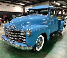 an old blue truck parked in a garage