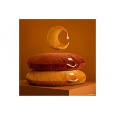 three pillows stacked on top of each other in front of an orange wall with a circular object above them