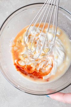 someone is mixing ingredients in a bowl with a whisk