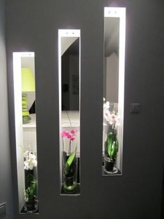 three vases filled with flowers sitting on top of a bathroom counter next to two mirrors