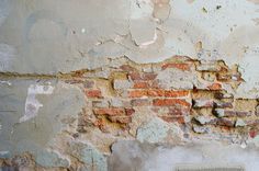 an old brick wall with peeling paint and chippings on it, in the background is a white fire hydrant