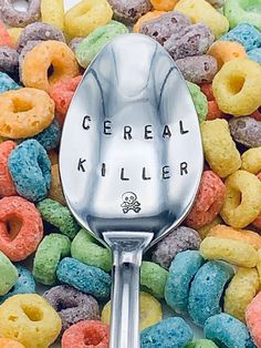 a spoon with cereal written on it sitting in front of a pile of colorful cereal