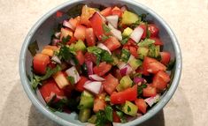 a blue bowl filled with lots of veggies on top of a white counter