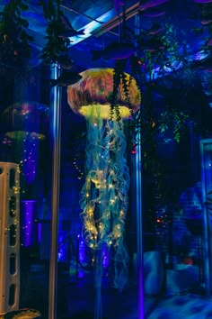 a large jellyfish hanging from the ceiling in a room with blue lights and plants