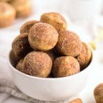 a white bowl filled with donuts sitting on top of a table next to other food items