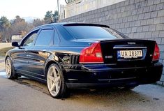 a black car parked in front of a brick wall