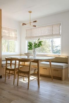 a dining table with four chairs and a bench in front of a window that has blinds on the windowsill