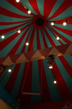 a large red and blue striped tent with lights on it's ceiling is lit up