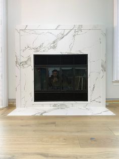 a white marble fireplace in a room with wood floors