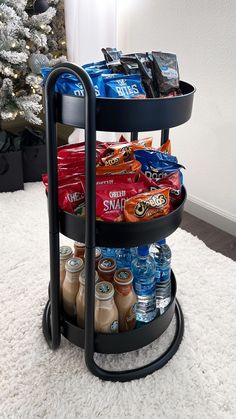 a three tiered tray with snacks and drinks on it in front of a christmas tree