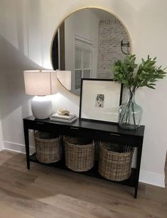 a black table with baskets and a mirror on top of it next to a lamp