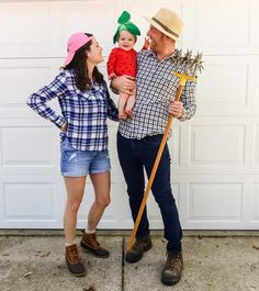 a man holding a baby and standing next to a woman in front of a garage door