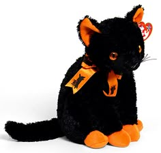 a black cat stuffed animal with an orange ribbon around its neck and eyes, sitting on a white surface