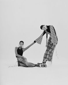 two women sitting on the ground with their legs wrapped around each other and one holding her leg