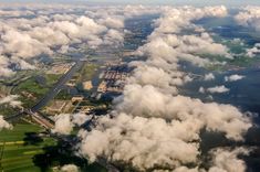 the view from an airplane looking down on some clouds and land in the foreground