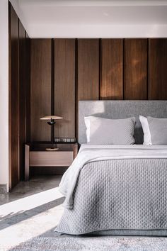 a bedroom with wood paneled walls and a large bed in the center, along with two nightstands on either side