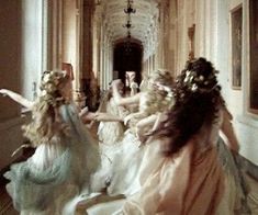 a group of women dressed in white and pink dresses are dancing with their arms around each other