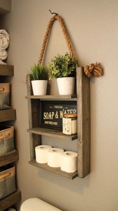 a wooden shelf with some plants and toilet paper on it next to a white toilet